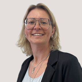 Yvonne Hartig Das Portrait zeigt Yvonne Hartig. Sie hat schulterlange blonde Haare und eine große Brille. Sie lächelt freundlich.